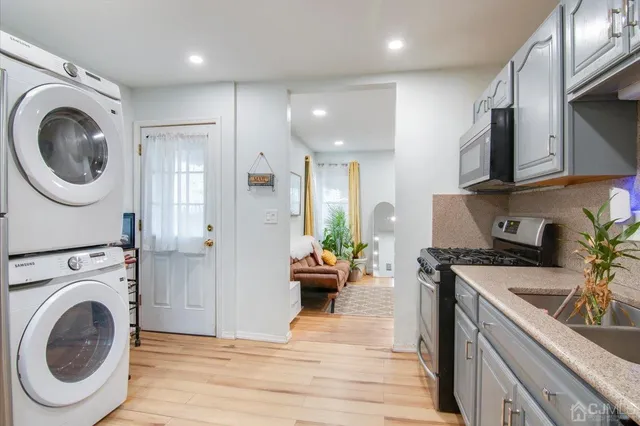 a view of a kitchen with a sink a stove top oven and wooden floors