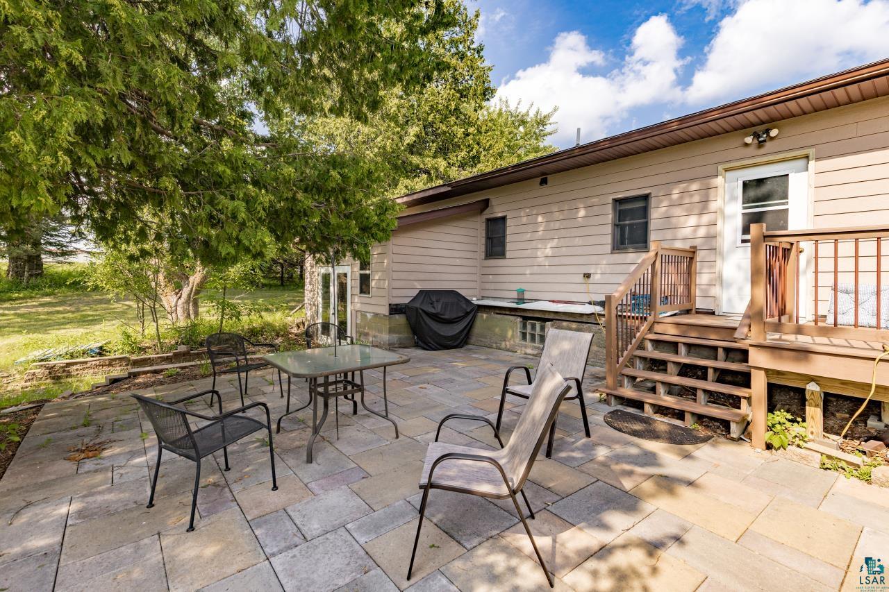 4800 Tower Road Moose Lake, MN 55767 - Photo 53 of 83 Expansive stone patio with varying paver sizes, featuring a wooden deck with railing and stairs