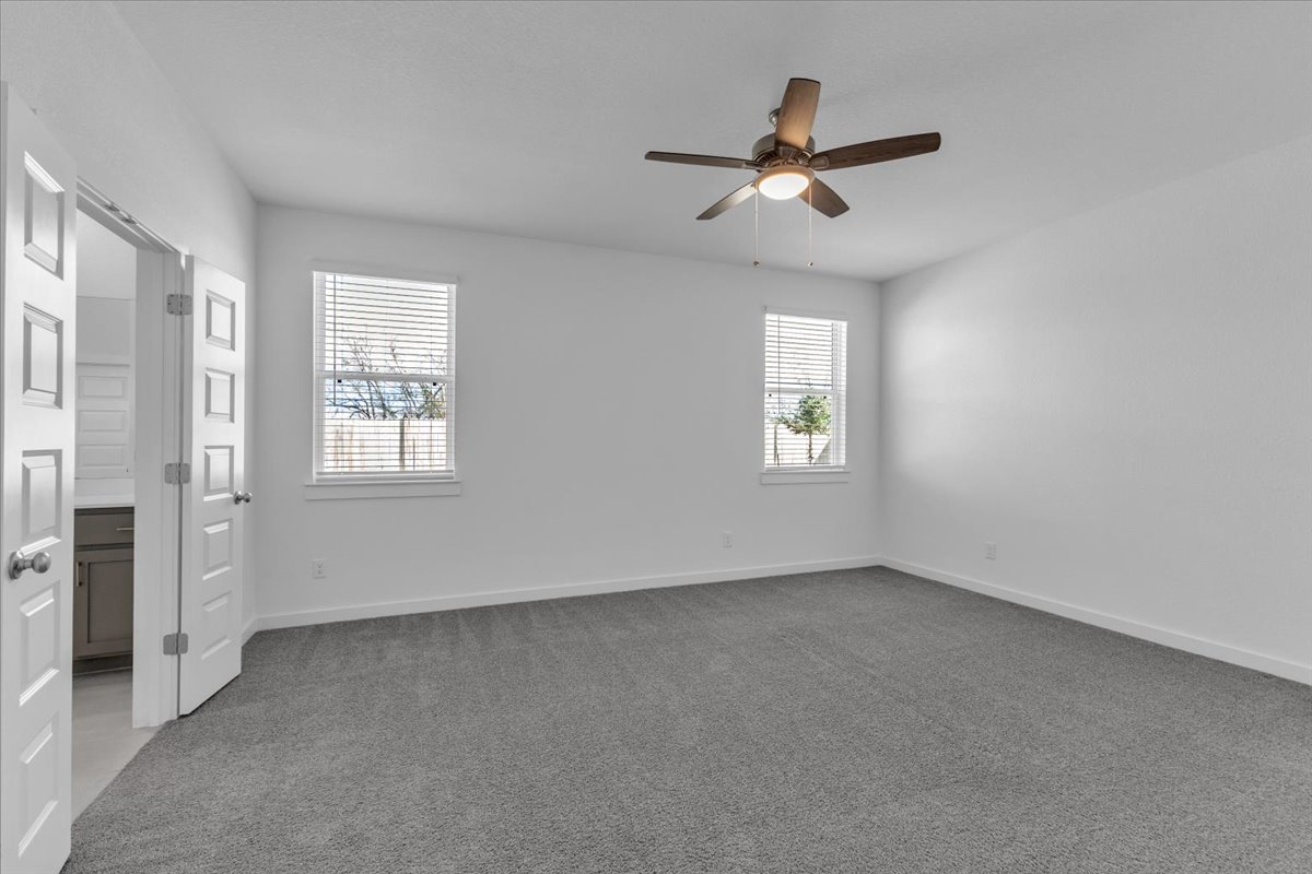 12620 Penguin Path Manor Manor, TX 78653 - Photo 19 of 37 Unfurnished bedroom with light colored carpet, ensuite bath, and a ceiling fan