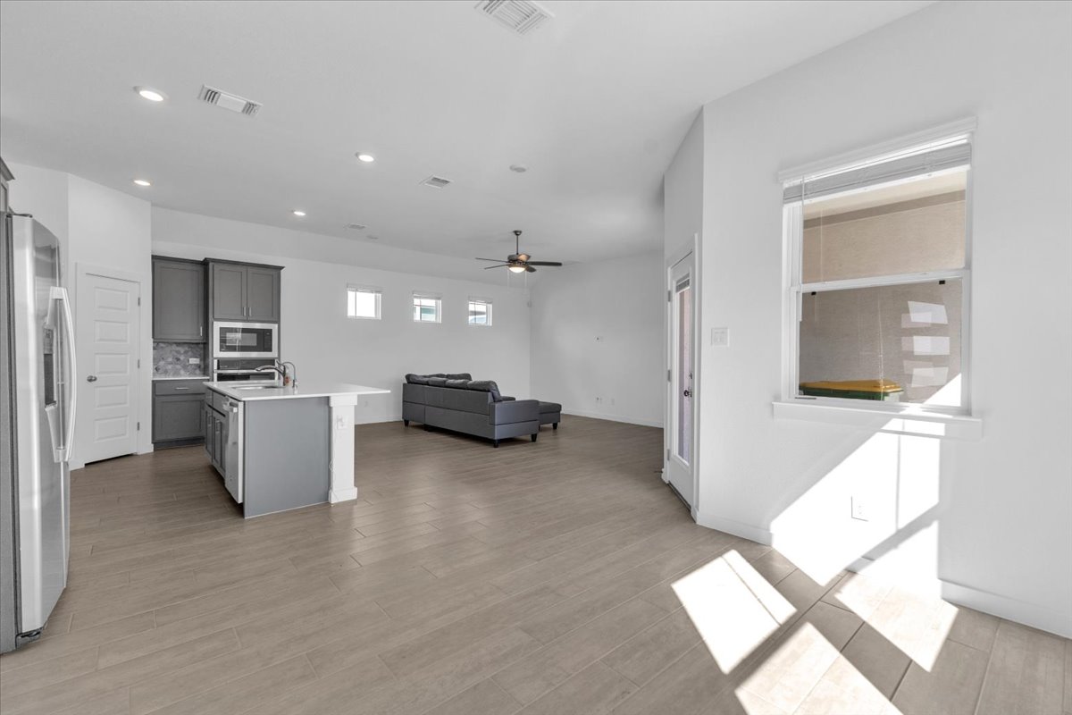 12620 Penguin Path Manor Manor, TX 78653 - Photo 33 of 37 Kitchen with stainless steel appliances, open floor plan, gray cabinets, light wood-style floors, and a kitchen island with sink