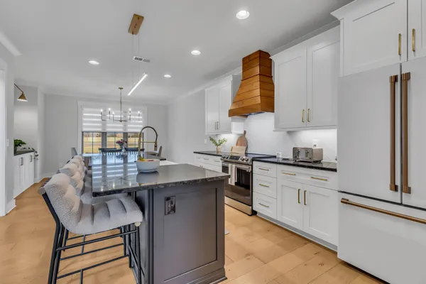 a large kitchen with stainless steel appliances granite countertop a lot of counter space and wooden floors