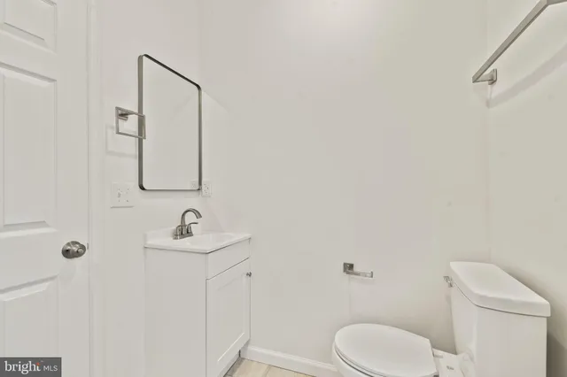 a bathroom with a toilet sink vanity and mirror
