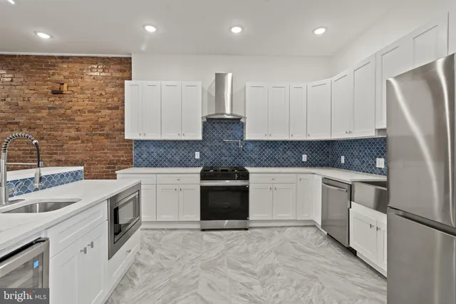 a large kitchen with stainless steel appliances granite countertop a stove a sink and a refrigerator