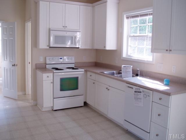 5904 Wynmore Road Raleigh, NC 27610 - Photo 4 of 10 a kitchen with white cabinets and white appliances