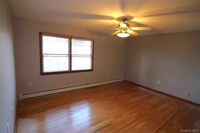 a view of a room with a large window a ceiling fan and wooden floor
