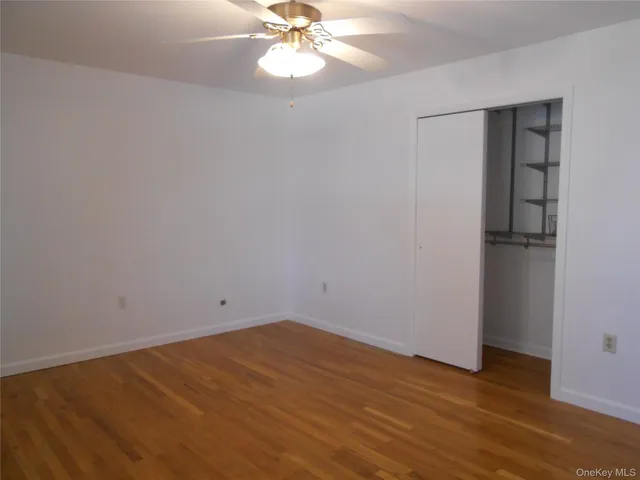 a view of a room with wooden floor and a ceiling fan