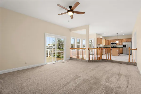 an empty room with windows and chandelier fan