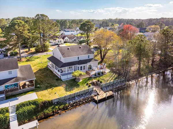 a view of a wooden deck next to a yard with large trees