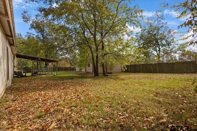 a view of a yard in front of a house with large trees