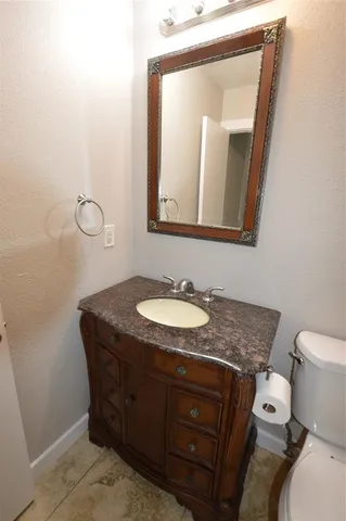 a bathroom with a granite countertop sink a mirror and toilet
