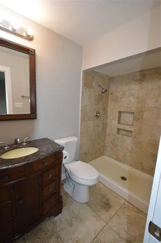 a bathroom with a granite countertop sink a toilet and a mirror