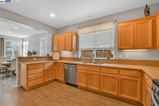a kitchen with stainless steel appliances granite countertop wooden cabinets a sink a stove a dining table and chairs