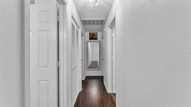 a view of a hallway with wooden floor and closet