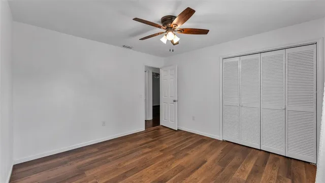an empty room with wooden floor and ceiling fan