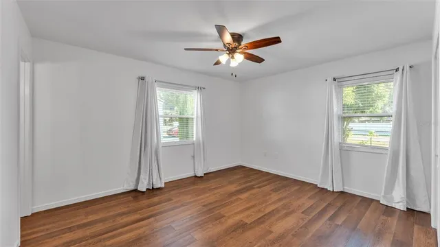 a view of empty room with wooden floor and fan