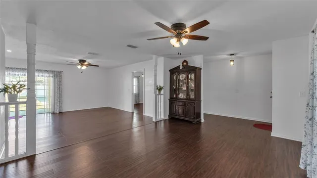 a view of an empty room with window and wooden floor