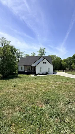 a front view of house with yard and trees in the background