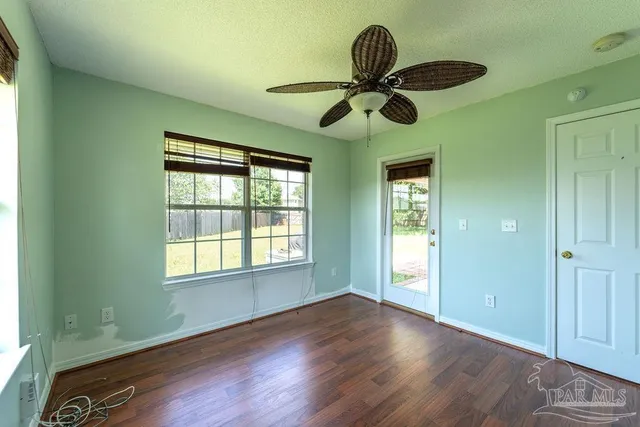 a view of an empty room with wooden floor and window
