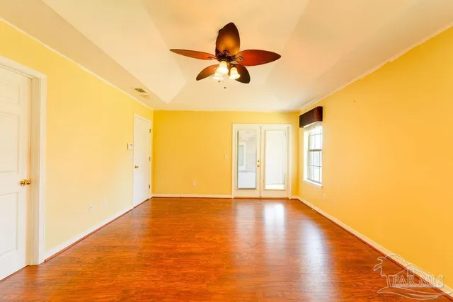 a view of empty room with wooden floor and fan