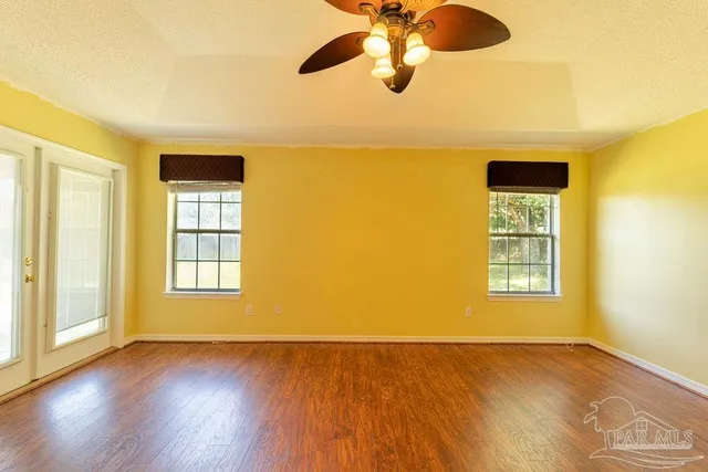 a view of an empty room with a window and wooden floor