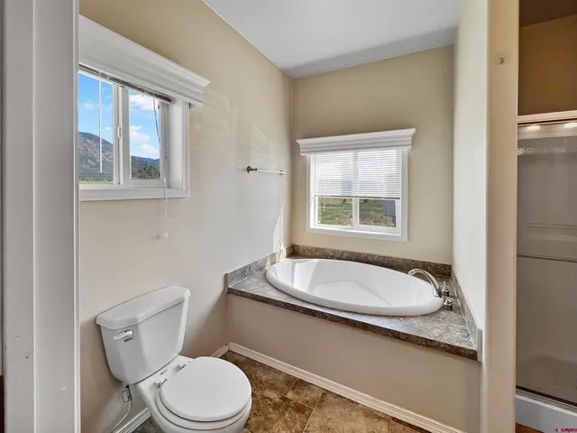 a bathroom with a granite countertop toilet a sink and a window