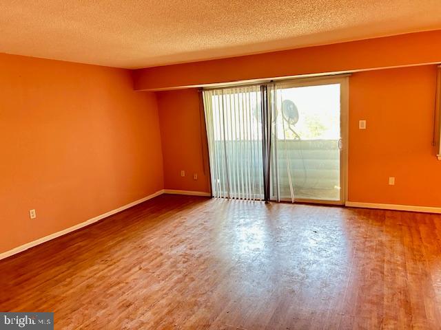 3 Windblown Court, Unit 102 Baltimore, MD 21209 - Photo 9 of 18 an empty room with wooden floor and windows with curtains