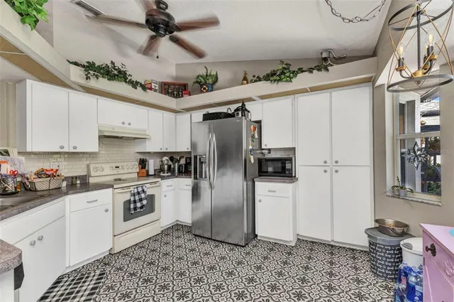 a kitchen with stainless steel appliances granite countertop a refrigerator a stove a sink dishwasher and white cabinets with wooden floor