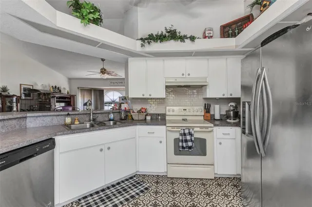 a kitchen with stainless steel appliances granite countertop a sink a stove a refrigerator and cabinets