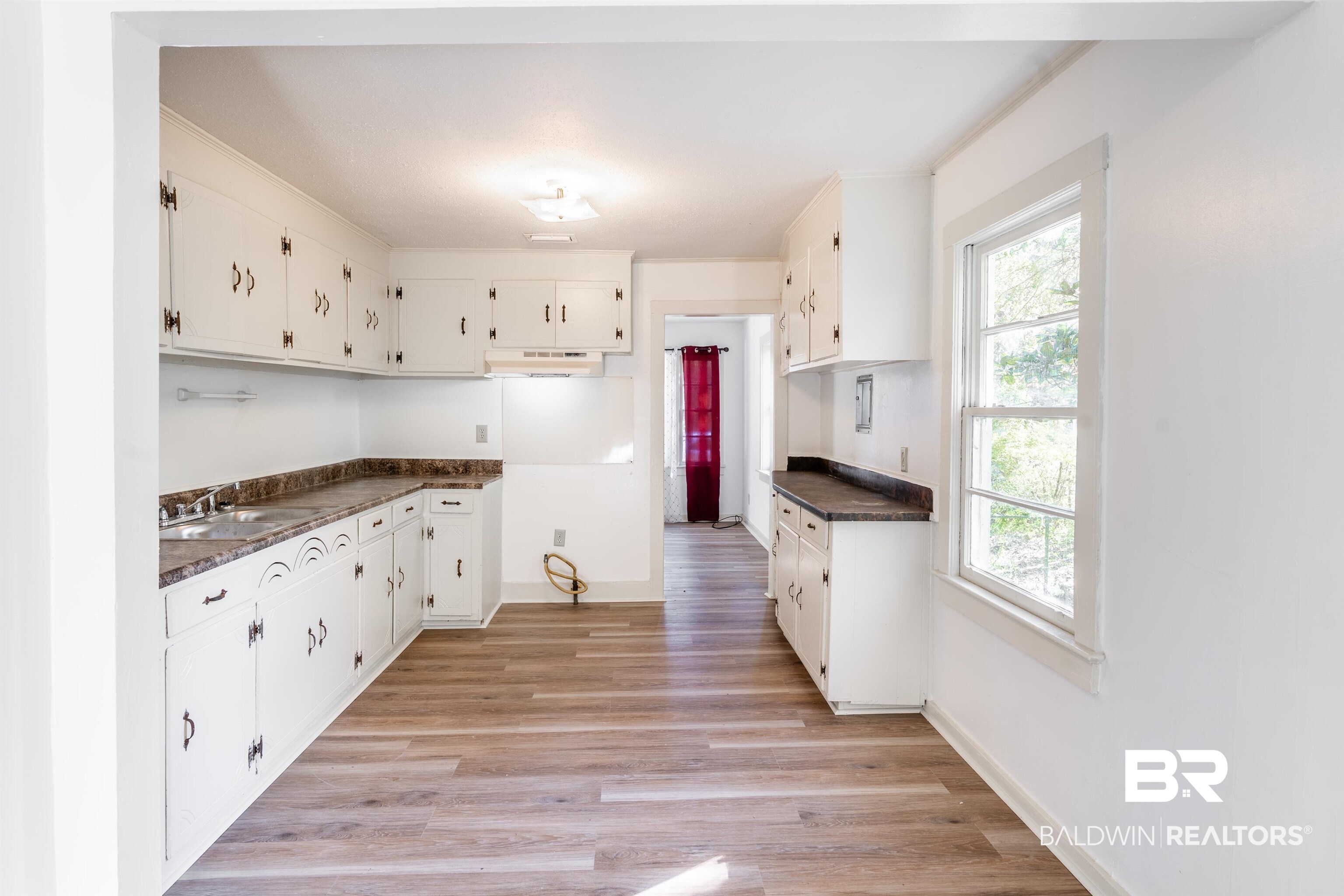 3900 Brookmont Drive Mobile, AL 36605 - Photo 5 of 19 Kitchen featuring sink, dark stone counters, light hardwood / wood-style flooring, and white cabinetry