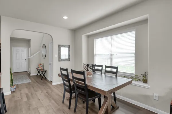 a kitchen with a dining table chairs wooden floor appliances and cabinets
