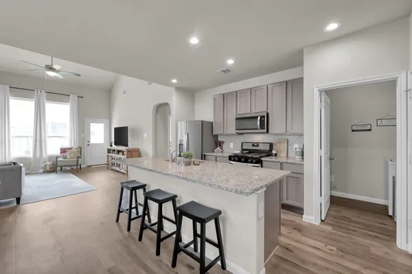 a open kitchen with stainless steel appliances granite countertop a lot of counter space and a wooden floor