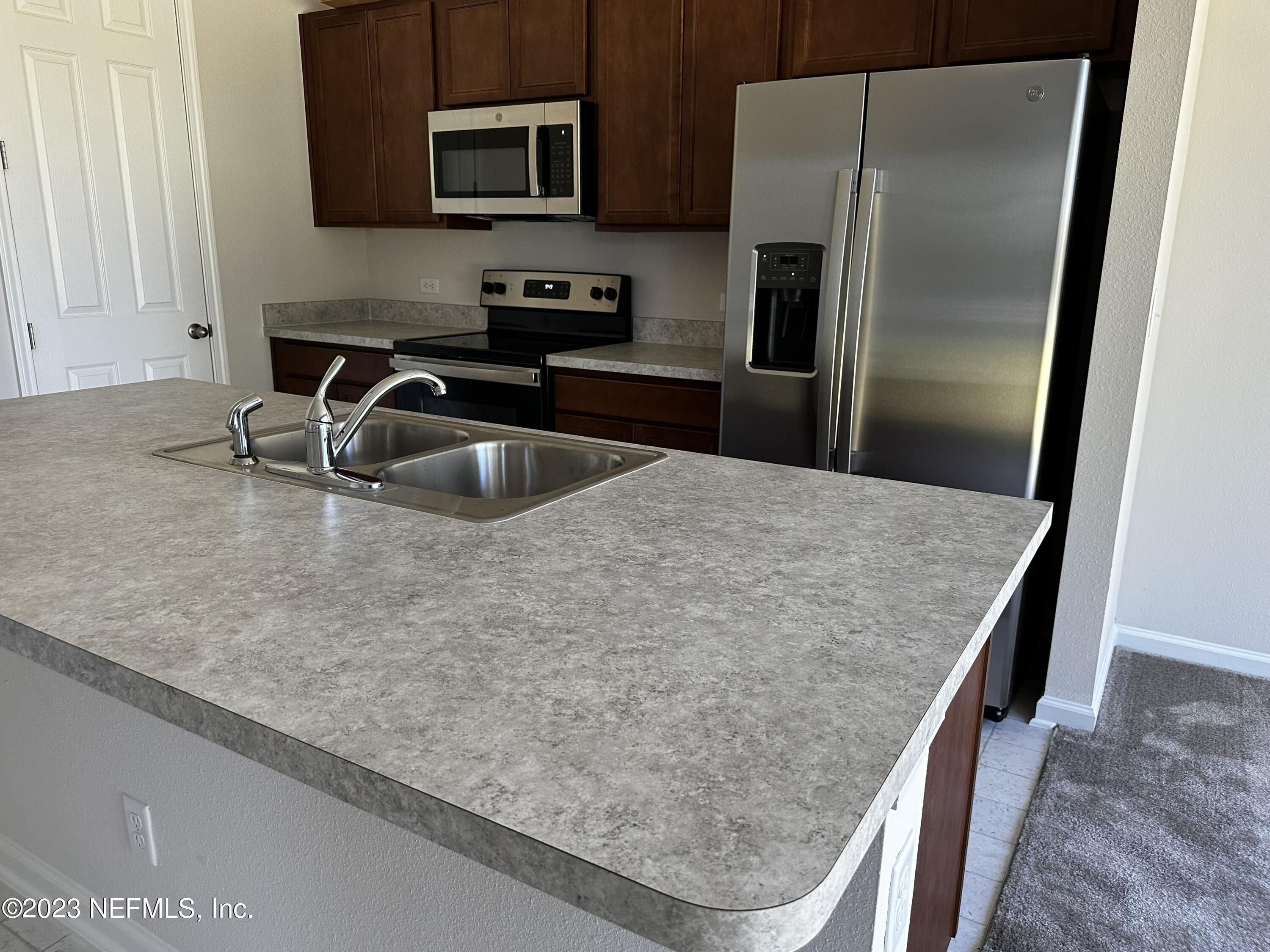 5138 Sawmill Point Way Jacksonville, FL 32210 - Photo 4 of 5 a kitchen with stainless steel appliances granite countertop a sink a refrigerator and a granite counter tops