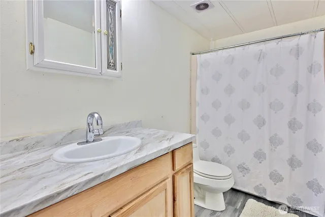 a bathroom with a granite countertop sink a toilet and a mirror