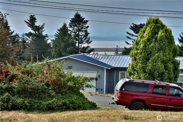 a view of a house with a cars park side of a road