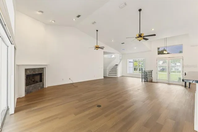 a view of an empty room with wooden floor fireplace and a window