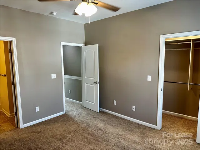 an empty room with closet and a chandelier fan