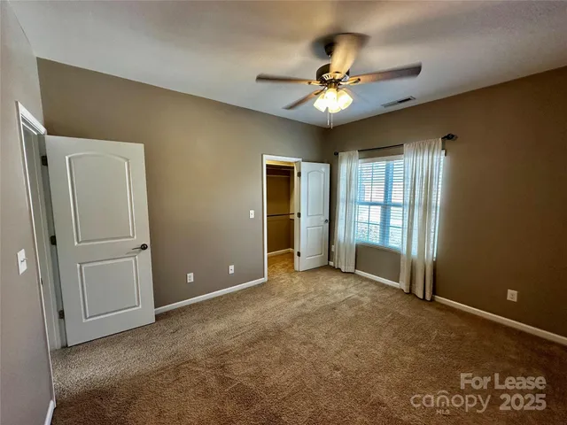 an empty room with chandelier fan and windows