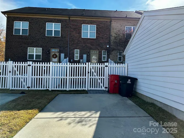 a view of a brick house with a small yard and wooden fence