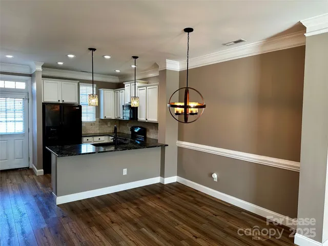a kitchen with a refrigerator and a wooden floor