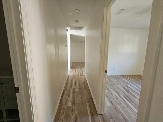 a view of a hallway with wooden floor and closet