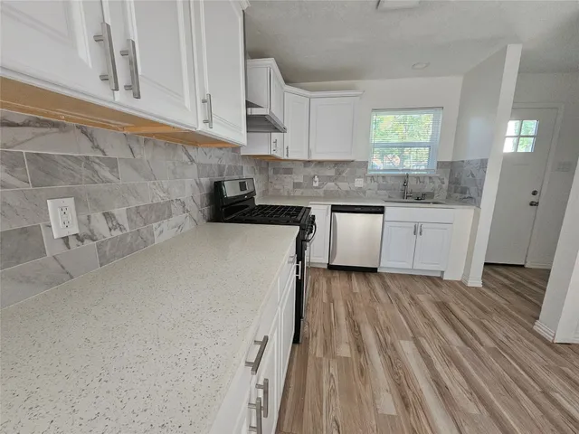 a kitchen with a sink a stove cabinets and wooden floor
