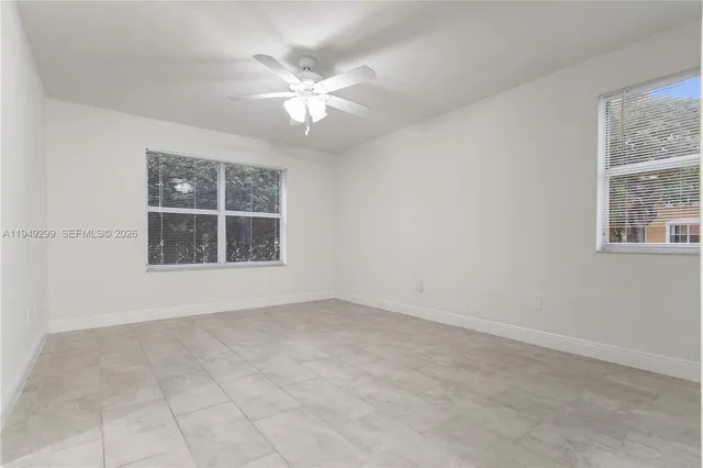 an empty room with windows and chandelier fan