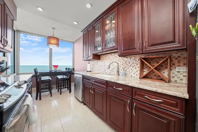 a kitchen with stainless steel appliances granite countertop wooden cabinets a dining table and chairs