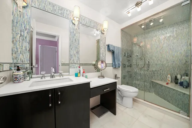 a bathroom with a double vanity sink toilet mirror and shower