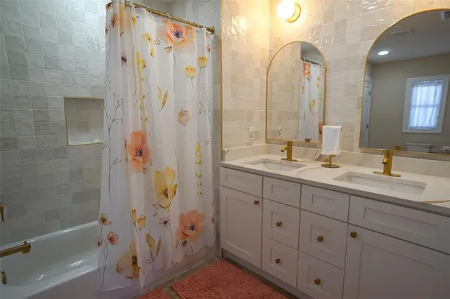 a bathroom with a double vanity sink a mirror a bathtub and shower