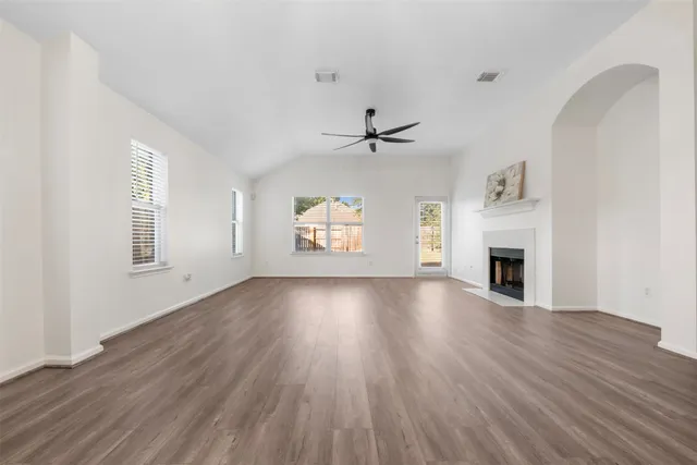 an empty room with windows fireplace and wooden floor