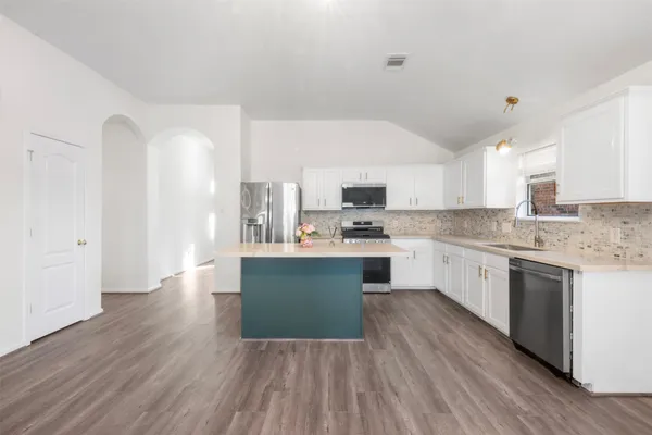 a kitchen with granite countertop a sink cabinets and wooden floor