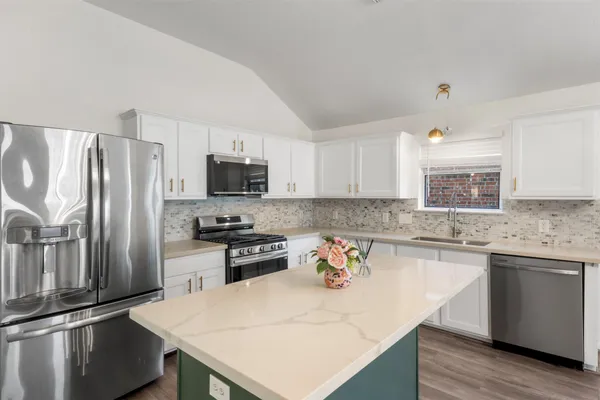 a kitchen with granite countertop a sink stove and refrigerator