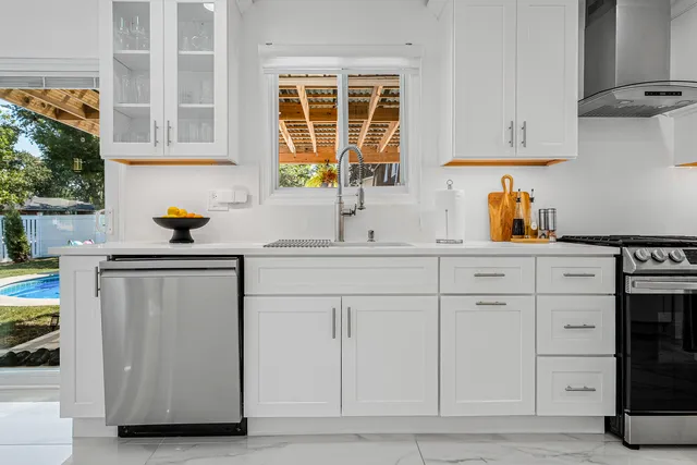a kitchen with white cabinets and a window