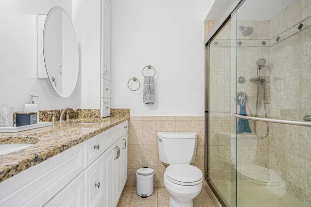 a bathroom with a granite countertop sink mirror vanity and toilet